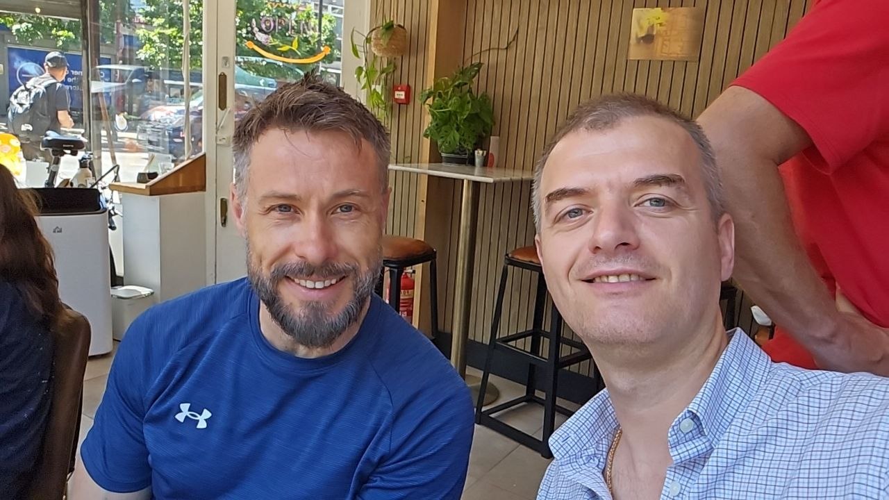 Two friends smiling together in a bright café setting.